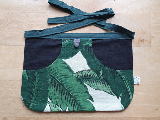 Peg bag with large green leaves. Black backing and green waste tie.